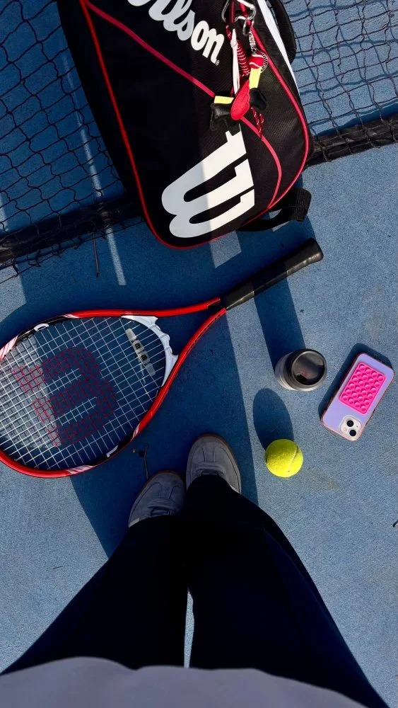 Tennisracket, ballen en telefoon met de REQUR-app